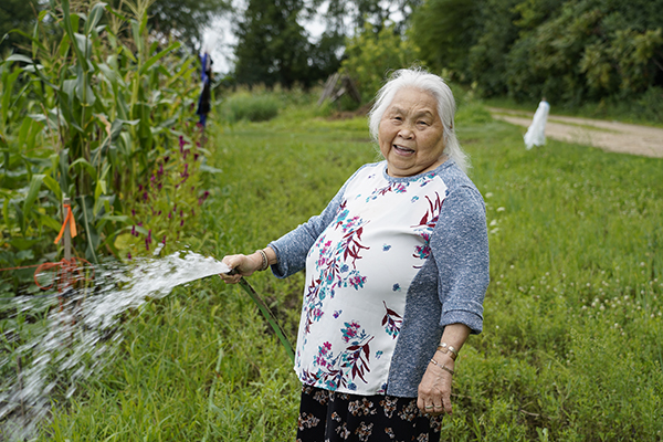  Xao Cha watered her vegetables with a garden hose as soon as the spigots were installed and ready for use.
