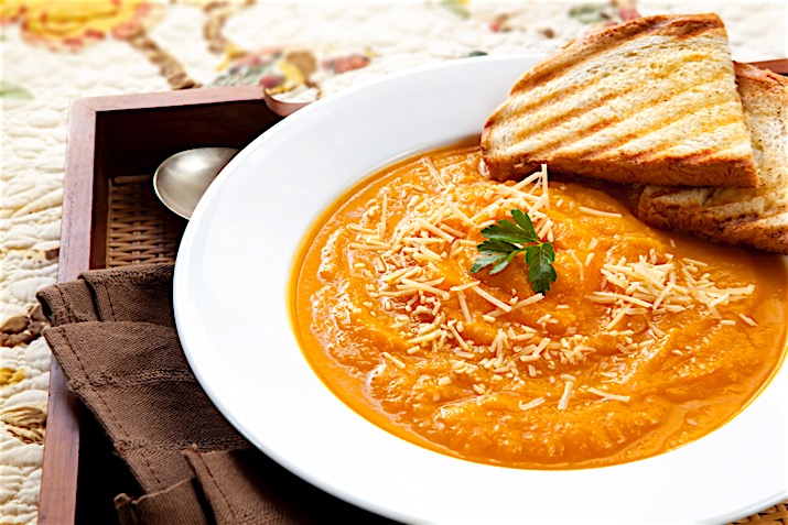 Pumpkin soup with parmesan cheese and crusty toasted bread, on a serving tray.  