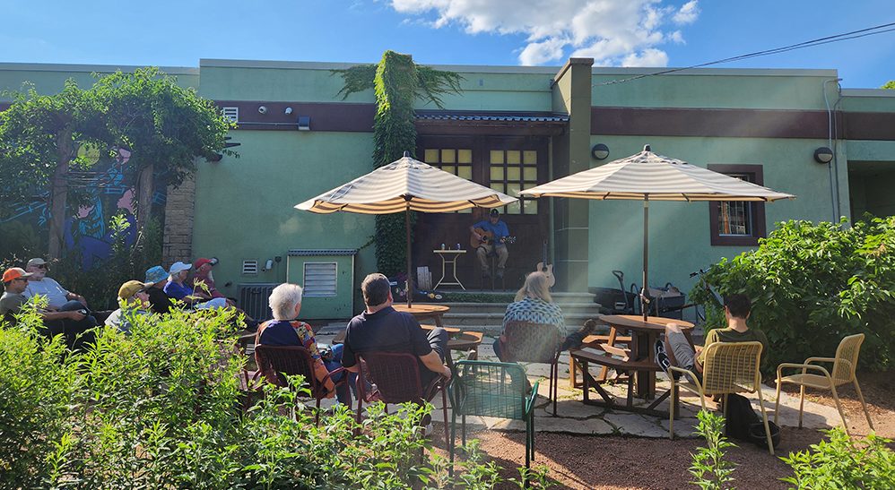 Rain Garden Sessions event with a guitar player playing to a small crowd.