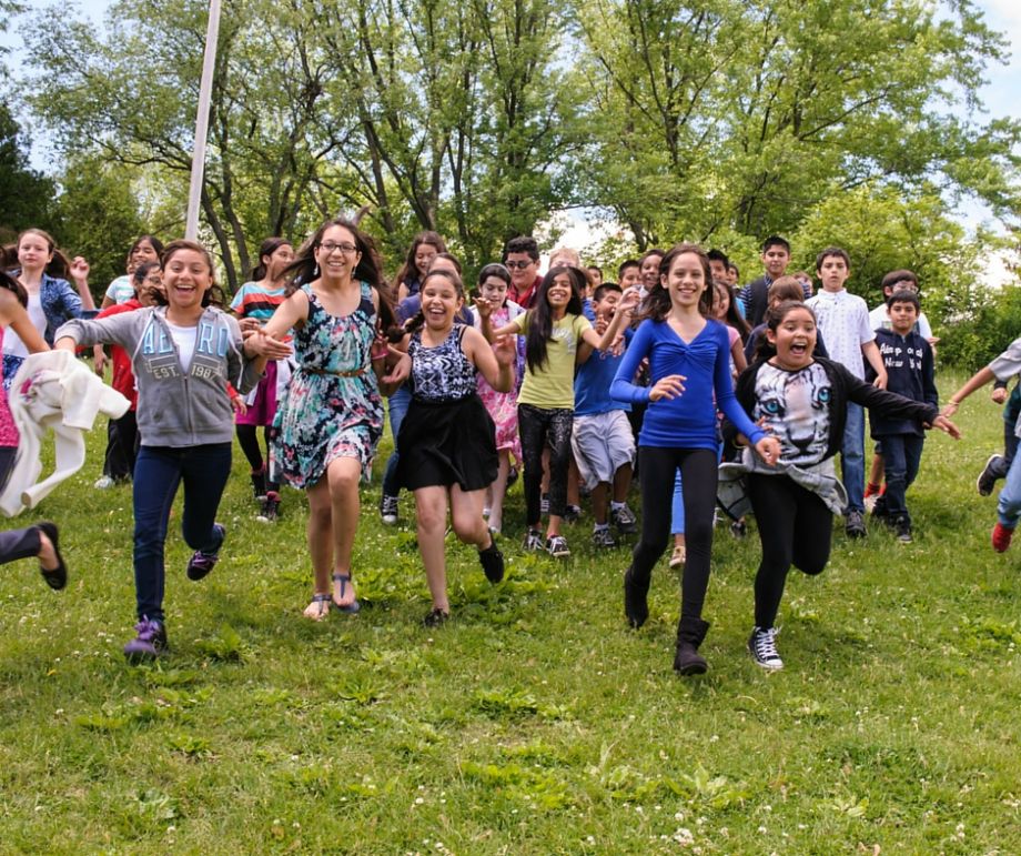 Smiling young kids run toward the camera.