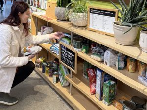 Person adding products to the food donation shelf at Willy East.