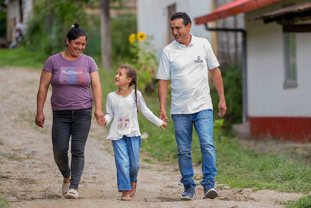 Gerardo and his wife hold hands with their young daughter